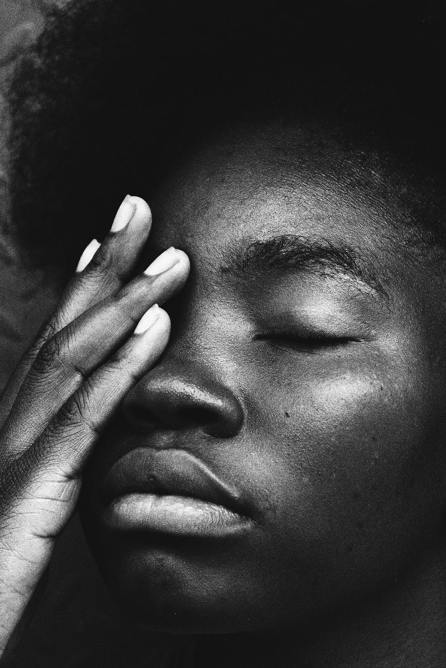 wistful black woman with eyes closed touching face in thoughts